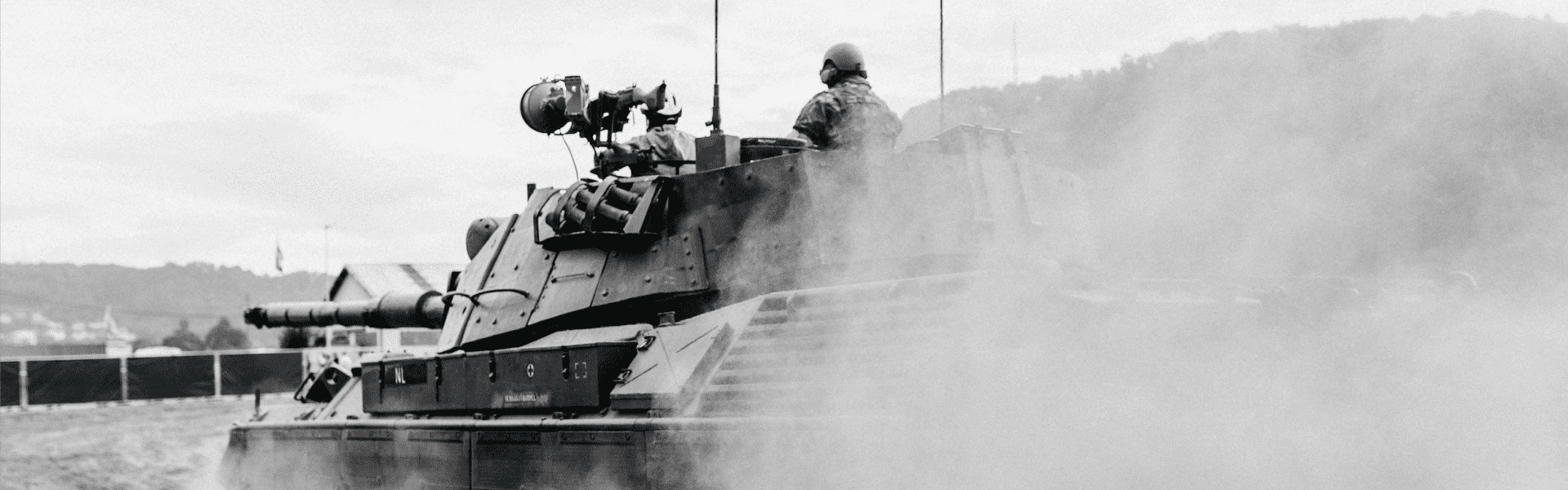 a black and white photo of a tank and a few people driving it